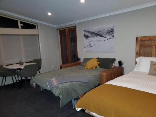 a bedroom with two beds and a table and a table at Lakeside Studio in Jindabyne