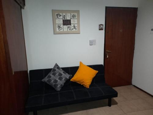 門多薩的住宿－Departamento Céntrico en Mendoza，一张黑色沙发,上面有两个黄色枕头