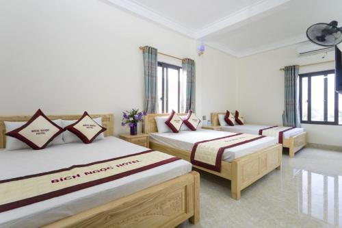 three beds in a room with windows at Bích Ngọc Hotel Quan Lạn - Thứ 7 nhận 5 phòng trở lên in Làng Liễu