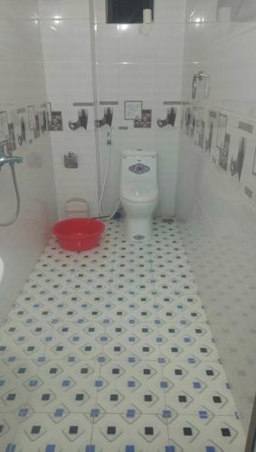 a bathroom with a toilet and a red bucket at Bích Ngọc Hotel Quan Lạn - Thứ 7 nhận 5 phòng trở lên in Làng Liễu