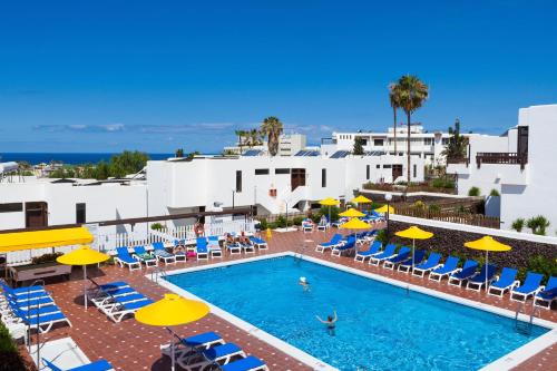 an outdoor swimming pool with umbrellas and chairs at Paraiso del Sol y Paradero in Playa de las Americas