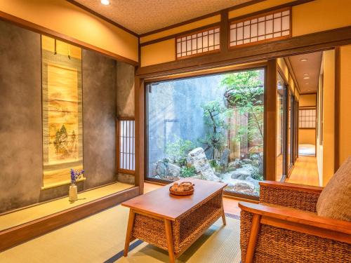 a living room with a large window and a table at 慶有魚·松家(Kyotofish·Matsuya)*经典松树中庭*鸭川畔独栋地暖百年町屋*门前高濑川 in Kyoto