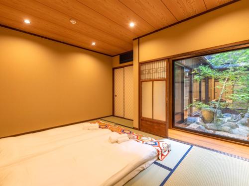 a bed in a room with a large window at 慶有魚·松家(Kyotofish·Matsuya)*经典松树中庭*鸭川畔独栋地暖百年町屋*门前高濑川 in Kyoto