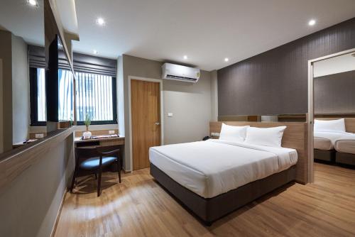 a hotel room with a bed and a desk at Almas Hotel Bangkok in Bangkok