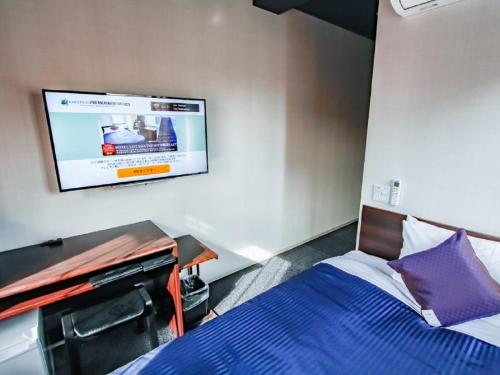 1 dormitorio con 1 cama y TV de pantalla plana en HOTEL LiVEMAX PREMIUM Umeda EAST en Osaka