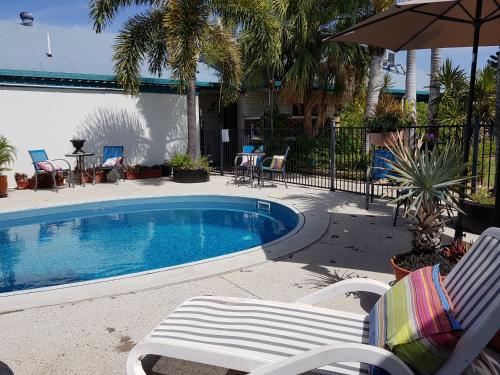a swimming pool with two chairs and an umbrella at Peppercorn Motel in Clermont