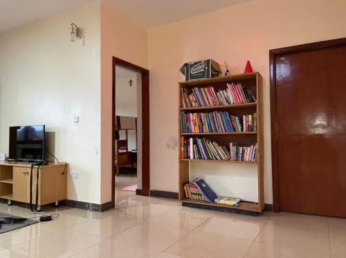 a room with a book shelf filled with books at The Mugabis Spacious Private Room in Kigali