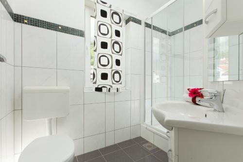La salle de bains blanche est pourvue d'un lavabo et d'une douche. dans l'établissement Room in BB - Delightfull room for 2, à Promajna