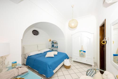 a white bedroom with a blue bed and a chair at Mamma Mia in Positano