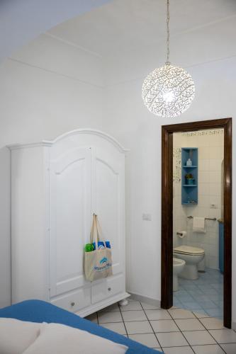a white bathroom with a toilet and a chandelier at Mamma Mia in Positano