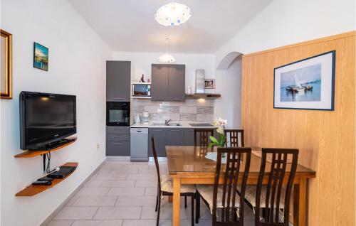 a kitchen and dining room with a table and a television at 2 Bedroom Amazing Apartment In Modric in Rovanjska