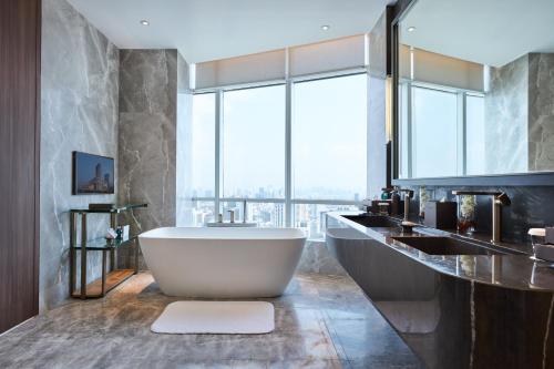 a bathroom with a tub and a large window at Centara Grand At CentralWorld in Bangkok