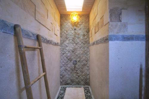 bagno con cabina doccia e parete in pietra di The Suci Sari Ubud ad Ubud