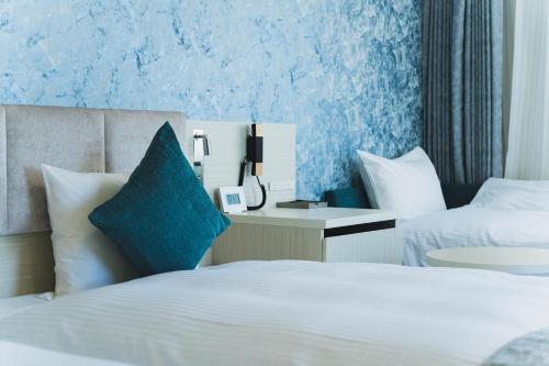 a hotel room with two beds and a phone at Rembrandt Style Naha in Naha