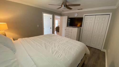 a bedroom with a white bed and a ceiling fan at Waterfront Hernando beach house on deep water canal w/dock, fishing, kayak in Hernando Beach