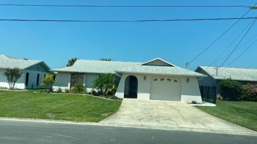 a white house with a garage on a street at Waterfront Hernando beach house on deep water canal w/dock, fishing, kayak in Hernando Beach