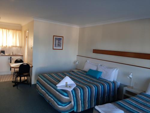 una camera d'albergo con due letti e un tavolo di Country Rose Motel Warwick a Warwick