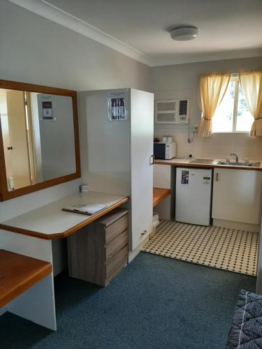 a small kitchen with a desk and a refrigerator at Country Rose Motel Warwick in Warwick