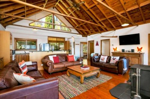 a living room with leather furniture and a flat screen tv at Narrow Neck Lodge in Katoomba