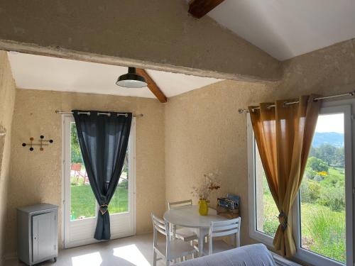 een kamer met een tafel, stoelen en ramen bij Cabanon entouré de montagnes et d'oliviers in Nyons