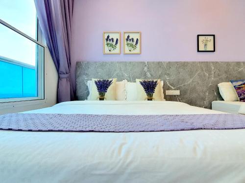a bedroom with a large white bed with purple walls at The Wave Suites Melaka in Melaka