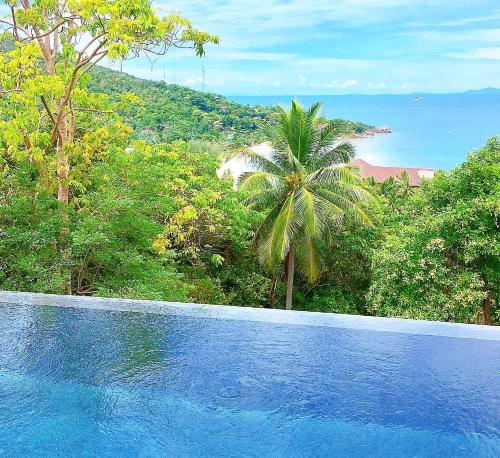 una piscina azul con vistas al océano en Bella & Palma Villas, en Haad Tian