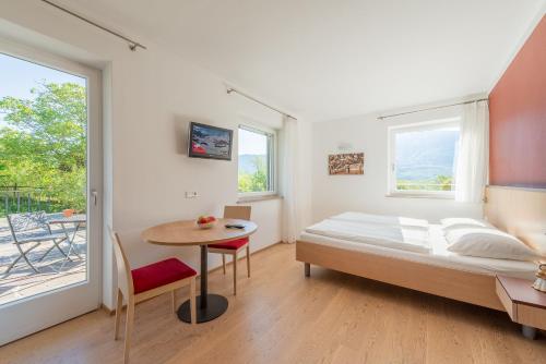 a bedroom with a bed and a table and window at Sandhof Ferienwohnungen in Termeno