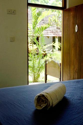 a towel laying on a bed in a room with a window at Freedom Beach Arugam Bay in Arugam Bay