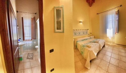 a bedroom with a bed and a bathroom with a sink at Su Massaiu in Turri