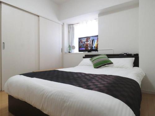 a bedroom with a large bed with a green pillow on it at Canaan Chuocho Building A in Kagoshima