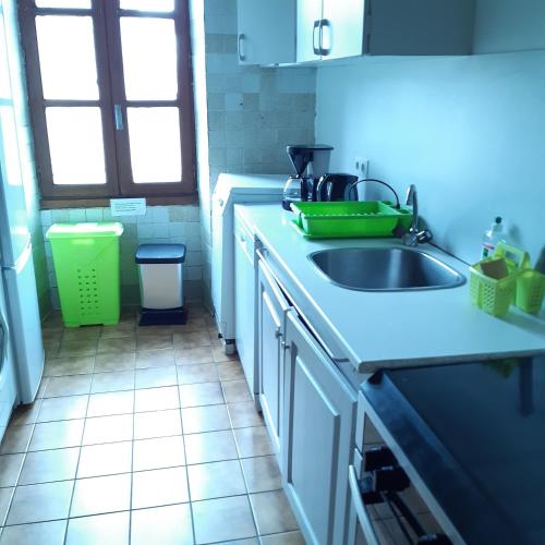 une cuisine blanche avec un évier et une fenêtre dans l'établissement ferme de Bournazel, à Bournazel