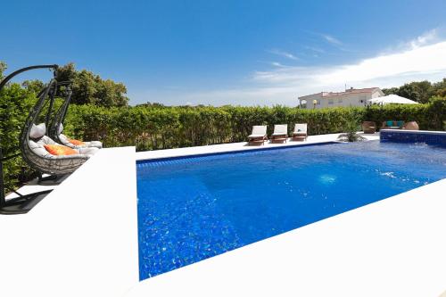 a swimming pool with a swing in a backyard at Villa Pino with Pool, Sauna & Jacuzzi in Petrcane
