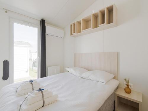 a white bedroom with a large bed and a window at Modern mobile home in Middelkerke with garden in Middelkerke