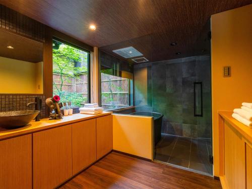 a bathroom with a sink and a shower with a window at Kyotofish·Masuya*Reformed Machiya*Gardenview Bath in Kyoto