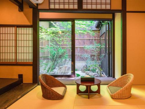 a room with two chairs and a table and a window at Kyotofish·Masuya*Reformed Machiya*Gardenview Bath in Kyoto