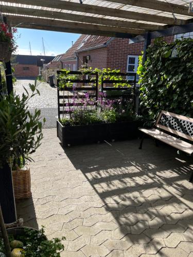 a patio with a bench and flowers in a garden at Færgestræde 45 in Marstal