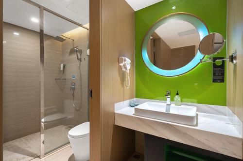 a bathroom with a sink and a mirror and a toilet at Ibis Styles XM Zhongshan Hotel in Xiamen