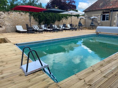 una piscina con una silla, mesas y sombrillas en LE CHARME DE ST PIERRE en Saint-Pierre-le-Moûtier