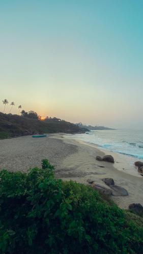 a beach with rocks and the ocean at sunset at Rockholm at the Light House Beach in Kovalam