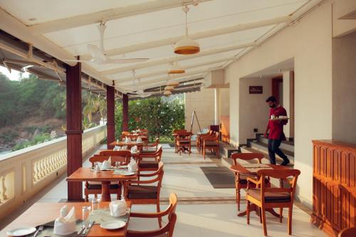 a man standing in a restaurant with tables and chairs at Rockholm at the Light House Beach in Kovalam