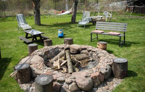 a fire pit in a yard with a bench and chairs at Dom całoroczny nad Bugiem in Wasilew Szlachecki