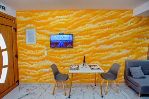 a room with a yellow wall with a table and chairs at RENT HOUSE ANEMOS in Iraklitsa