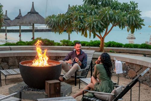 a man and a woman sitting around a fire pit at Preskil Island Resort in Blue Bay