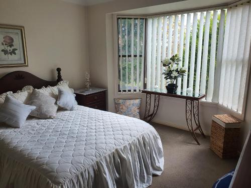 a bedroom with a white bed and a window at The Junction Estate COOL CALM COZY A Home N Host Property in Wallerawang