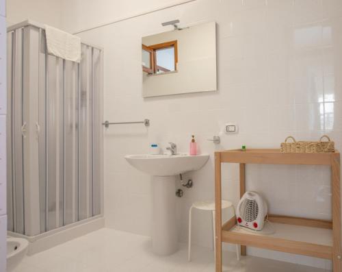 a white bathroom with a sink and a shower at Casa BabbaLuciana in Mondello
