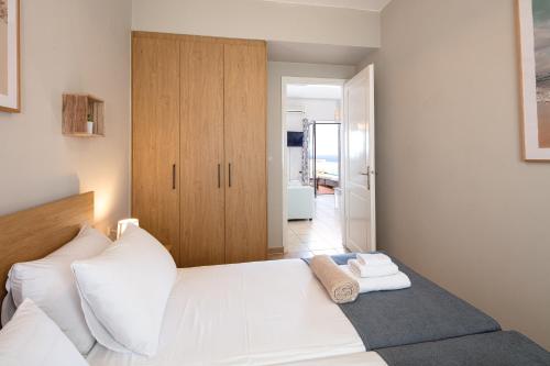 a bedroom with a white bed with a wooden cabinet at Plaka Modern Apartment in Chania Town