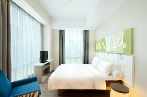 a bedroom with a bed and a blue chair at All Seasons Jakarta Thamrin in Jakarta
