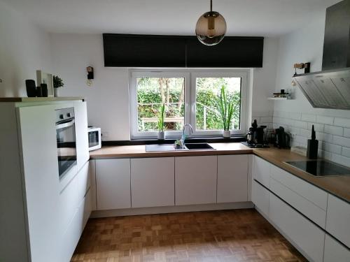 a kitchen with white cabinets and a sink and a window at Helle, moderne Ferienwohnung am Waldrand in Prüm für max 4 Personen in Prüm