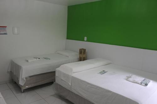two beds in a room with a green wall at Pousada Maramazon in São Luís