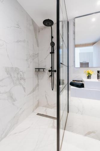 a bathroom with a shower with white marble walls at At Herbal Boutique Hotel & Spa in Protaras